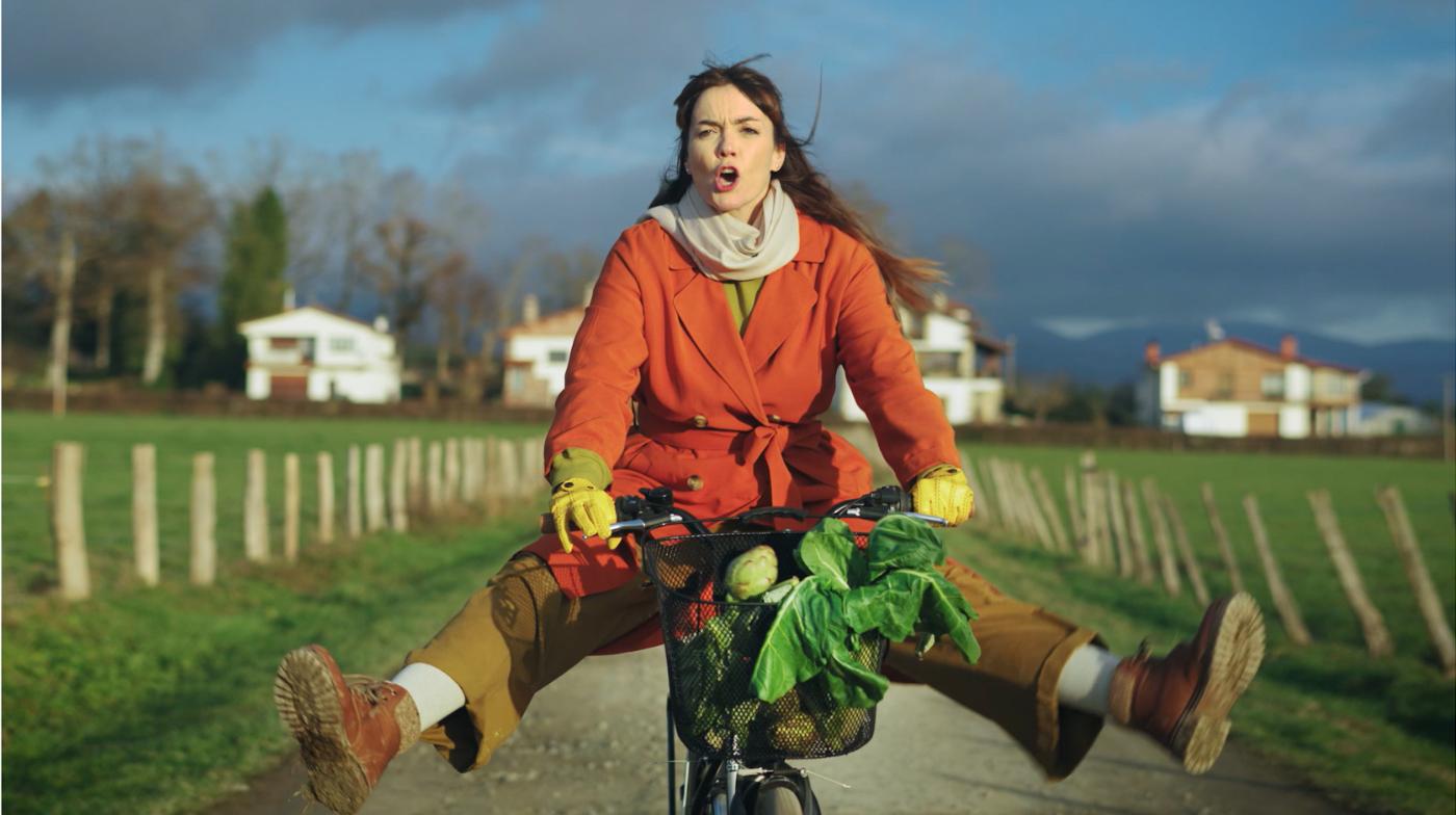 Chica en bicicleta con una cesta de alcachofas